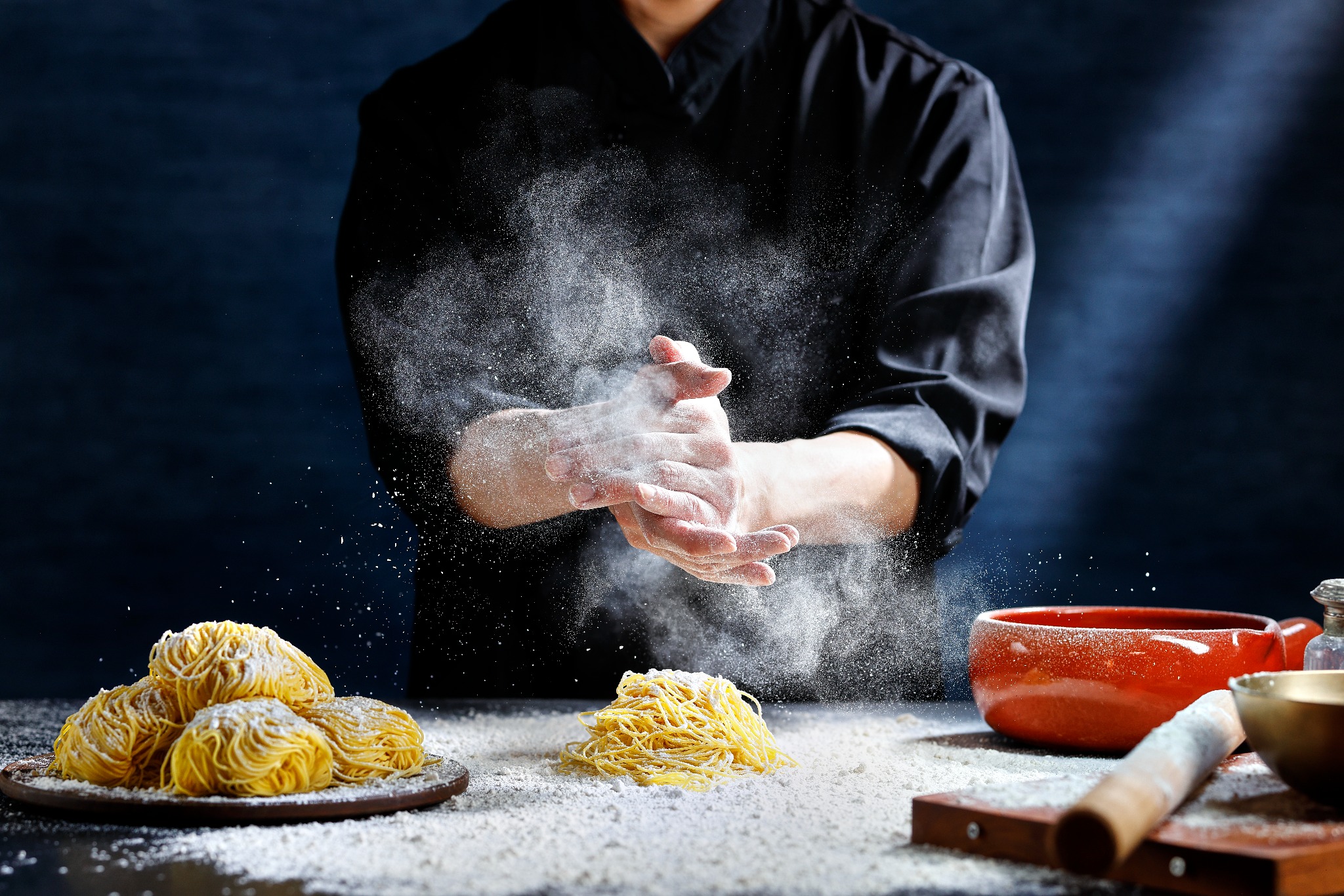 粉を舞わせながら麺を仕上げる料理人